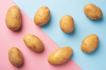 Fototapeta na wymiar Raw potato tubers on a pink and blue background.