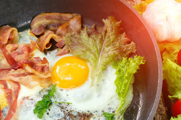 Fried eggs with crispy bacon in a pan with cherry tomatoes. Keto breakfast for keto diet.