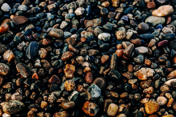 Texture of wet smooth pebbles on the seashore