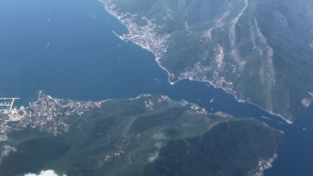 Aerial wide view from airplane of the Adriatic Sea in view in bay of Kotor in Montenegro slow motion. Flying over the sea and mountains on the plane. View from the aircraft to the Adriatic coast.