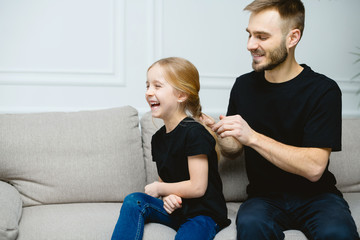 Young father arrange braid daughter hair indoors