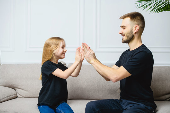 Young father and daughter play clap hands