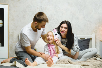 Happy young family smiling at home bed