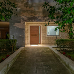 pathway to apartment building main entrance wooden door and window, night view