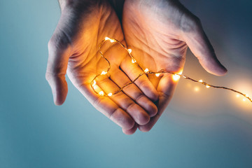 Mani tengono un simbolo del cuore acceso con luci