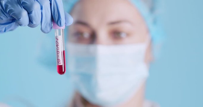Female laborant holding tube with samples of Covid-19