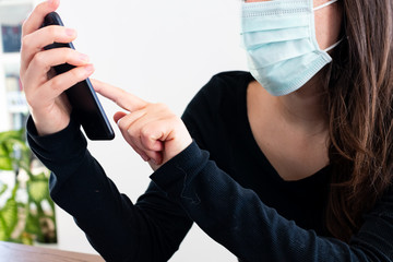 Creative business woman working at home during coronavirus covid-19 outbreak. Smart Working activities with smartphone under quarantine wearing a protective surgical mask. Smart working at home