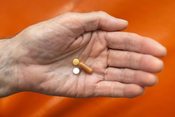 age, medicine, health care and people concept - close up of man cupped hand with pills at home or hospital