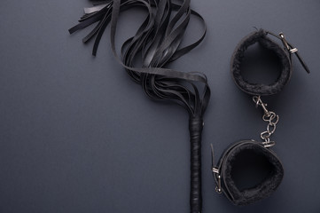 Accessories for bdsm on a black background. Leather lash and leather handcuffs. Valentine's Day....