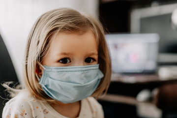a young child wearing a protective medical mask is home treated at home