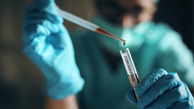 Conceptual video of a doctor taking samples from a test tube with a pipette, while testing for presence of coronavirus (COVID-19).