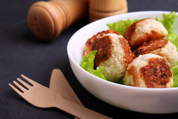 chicken cutlets with lettuce in a white plate on a black background