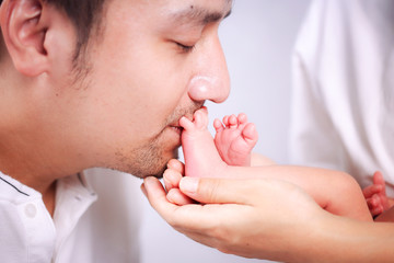 Father is kissing baby's feet. Happy loving father kisses feet of his newborn baby.