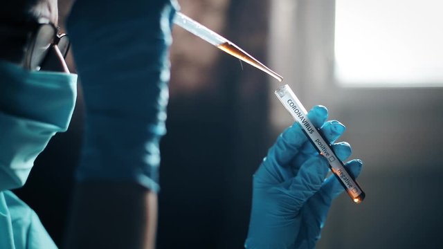 Conceptual panning video of a doctor taking samples from a test tube with a pipette, while testing for presence of coronavirus (COVID-19).