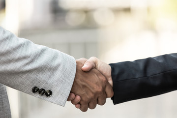 Closeup of business partners handshake. Business man and woman shaking hands with each other outside. Closing deal concept
