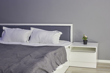 Comfortable bed with pillows in the room, in gray tones