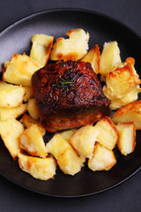 a piece of meat baked with potatoes on a black background
