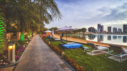 Small sandy beach at tropical resort with a view of Bahrain city