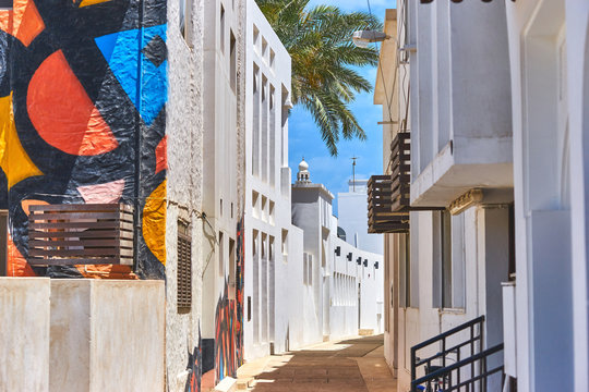 Narrow street with traditional white houses in the old district in Bahrain