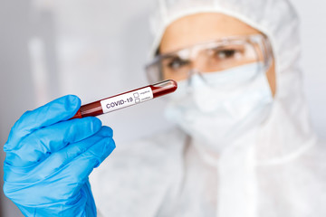 Covid 19 Coronavirus infected blood in tube in hand of scientist female doctor biohazard protection clothing in coronavirus research laboratory. Coronavirus Covid-19 vaccine research