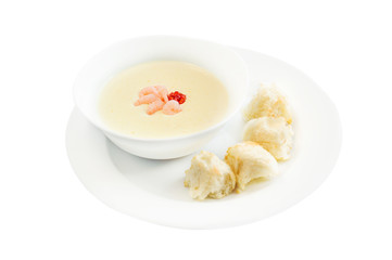 Vegetable cream soup with shrimps and croutons in white bowl