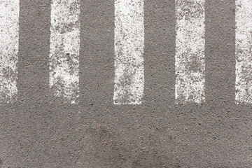 Asphalt with pedestrian crossing markings on it. White stripes on gray asphalt, taken from the top angle.
