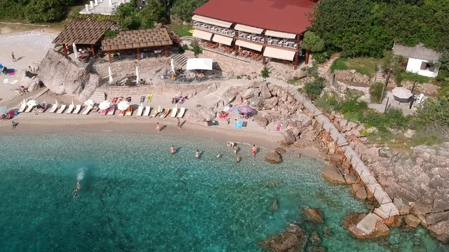 Aerial footage from a drone of people relaxing by the beach and swimming in the sea.