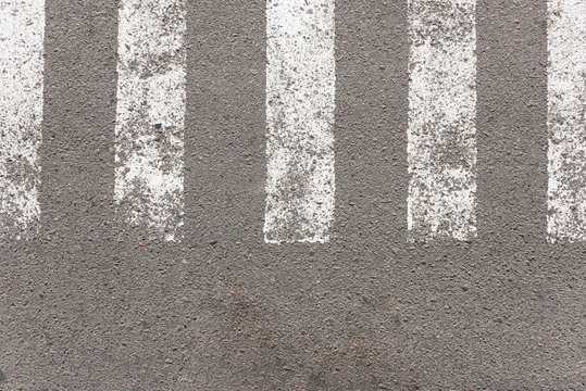 Asphalt with pedestrian crossing markings on it. White stripes on gray asphalt, taken from the top angle.