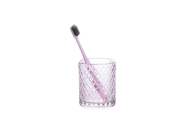 Pink toothbrush in a glass beaker isolated on white background.