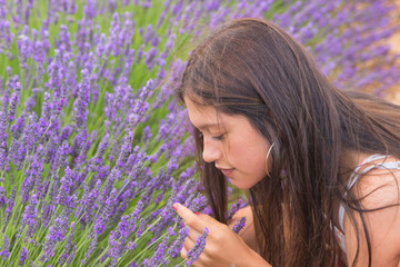 A teenager smelling a lavender flower in a sunny day