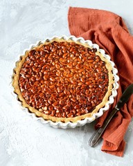 Tart with peanuts and condensed milk on a gray background