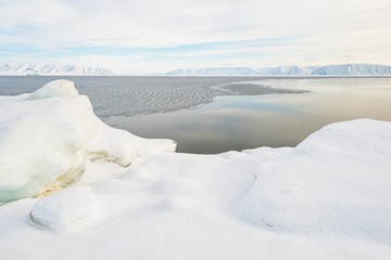 Open water at fjord in front of mountain range, Greenland.