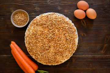 Carrot cake and fresh carrot on wooden table