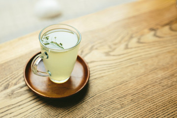 Picture or glass cup with green or white tea in it. Stand on plate. No people aroun. Daylight. Close up.