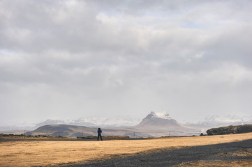 One person contemplating snowy mountains landscape in Dyrholaey peninsula (region of Sudurland, Iceland)