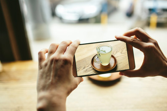 Yang women taking photo of green tea with smart phone
