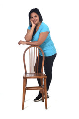 woman playing with a chair in white background, leaning on the chair