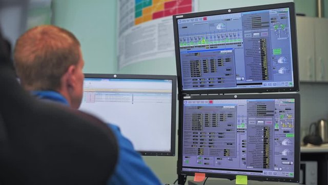 A worker sits in front of many monitors. Production room. Monitoring of technical processes in oil production. Instruments for monitoring indicators in the manufactory. Remote control.
