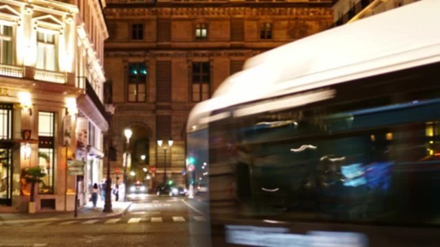 Time Lapse. Defocused view of a Parisian street. Heavy traffic. Large number of people cross the road. Nighttime. Traffic light. Beautiful old building in the background. Baroco facade. Ultra HD 
