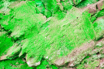 Green background. Wall with peeling plaster, tinted in green. Modern urban building concept. Bright neon backdrop. Selective focus
