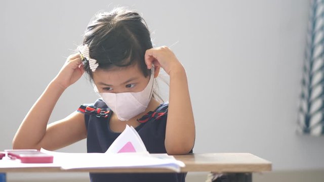 asian girl ware mask protech pm2.5 covid corona virus and working homework at home.