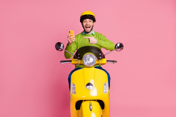 Portrait of his he nice attractive glad cheerful cheery guy riding motorbike showing cell fast speed internet web connection 5g isolated over pink pastel color background