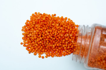 red lentils poured from a jar on a white background close-up. place for text. group. legumes. grocery