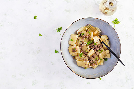 Pasta Calamarata with minced meat in blue bowl. Italian cuisine. Top view, overhead