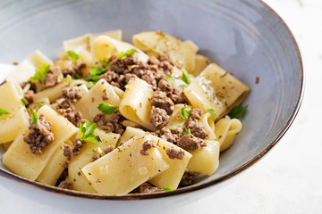 Pasta Calamarata with minced meat in blue bowl. Italian cuisine.