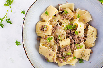 Pasta Calamarata with minced meat in blue bowl. Italian cuisine. Top view, overhead