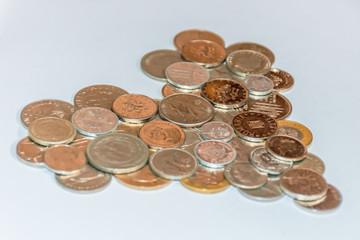 Assorted coins, both old ones which are no longer in circulation and contemporary ones which are used today, of various countries and currencies, laid out in a shape of a heart