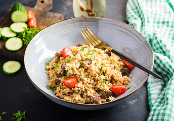 Bulgur pilaf with meat and and vegetables. Delicious healthy warm lunch on black background. Eastern cuisine.