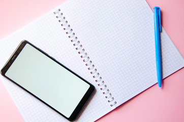 Notepad and smartphone and pen on a pink background. Notebook. Flatley.  Place for text.