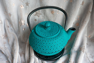 Turquoise cast iron teapot on beige background, side view